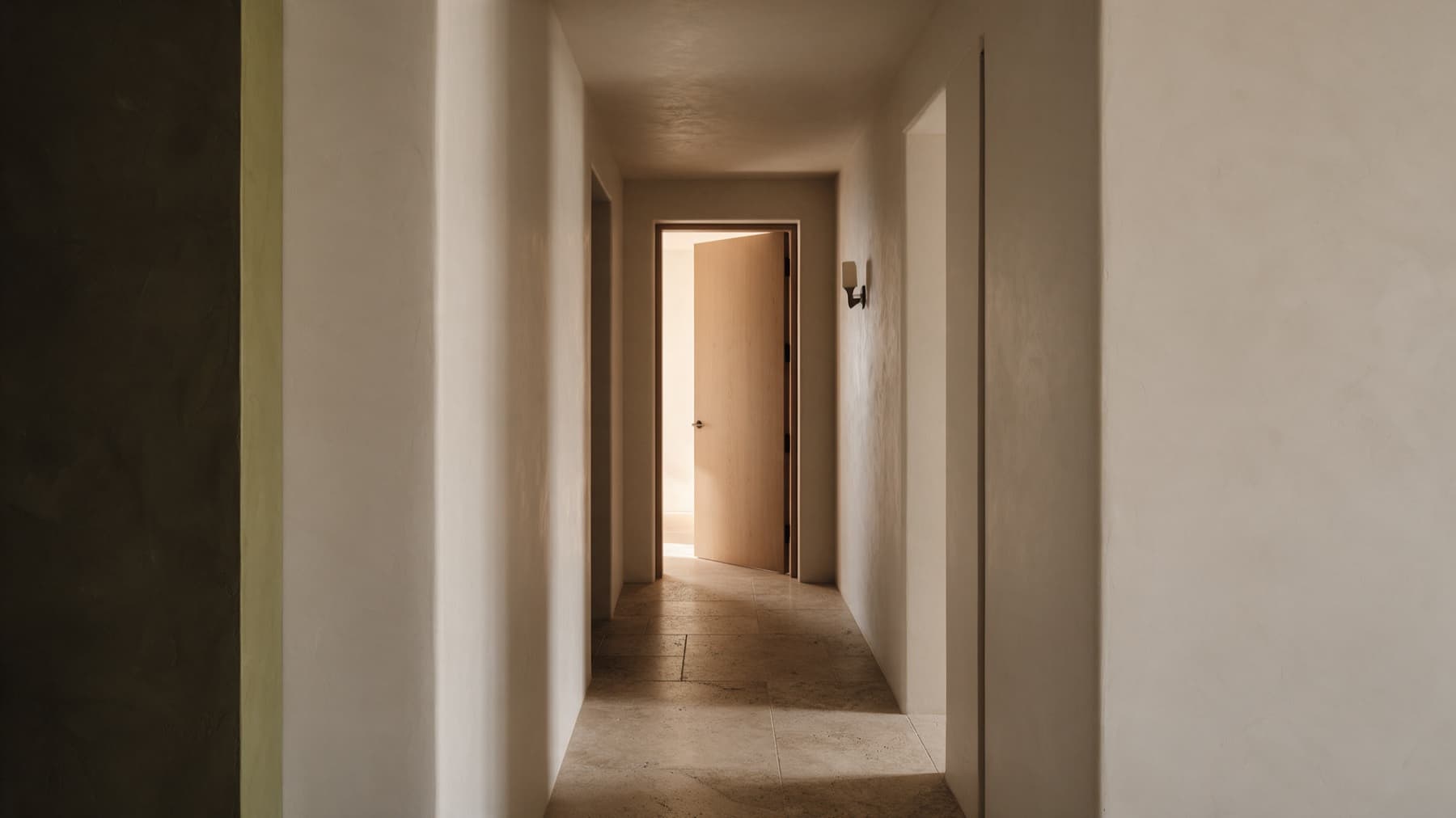 Pasillo despejado hacia una puerta abierta con luz al fondo