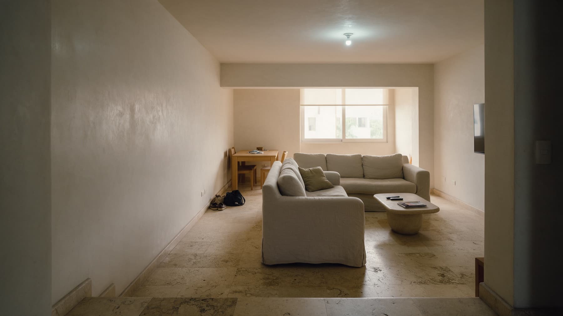 Recreación del antes: sofá flotando en medio de la sala de espaldas a la entrada, zapatos y bolsos junto a la puerta, comedor arrinconado y a oscuras